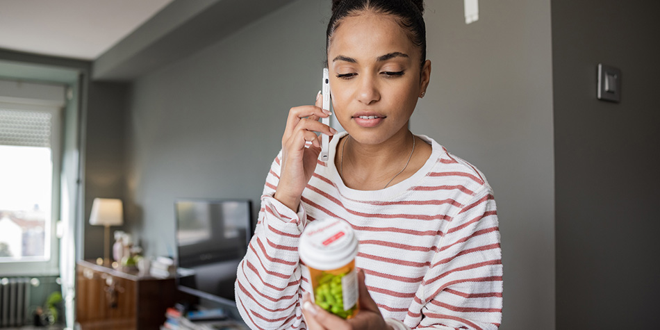 Woman holding a pill bottle and talking on the phone.