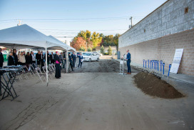 people look on as John Skevington, dressed in suit behind a podium addresses audience
